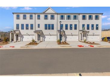 Three-story townhouses with white brick exterior and two-car garages at 214 Wilder Ridge Way, Lawrenceville, GA 30044