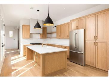 Bright kitchen with light wood cabinets, stainless steel appliances, pendant lights, and a large center island at 10931 Serenbe Ln, Chattahoochee Hills, GA 30268