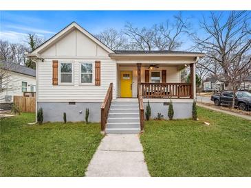 Charming home featuring a bright yellow door, shuttered windows, and a cozy, covered front porch at 1375 Miller Reed Se Ave, Atlanta, GA 30315