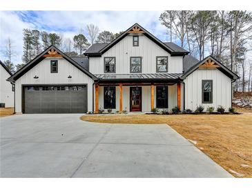 Two-story farmhouse with gray accents, a metal roof, and a large driveway at 3609 Centerville Rosebud Rd, Snellville, GA 30039