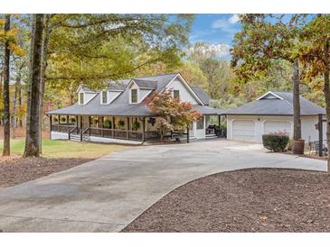 Charming home with a welcoming wrap-around porch, lush landscaping, and a detached two-car garage at 3380 Wildwood Rd, Suwanee, GA 30024