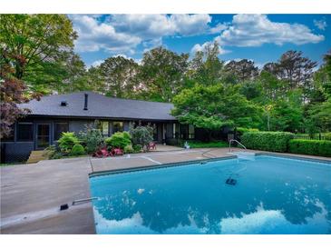 Inviting pool with a concrete surround and lush greenery, perfect for relaxing and entertaining guests at 110 Cove Ln, Social Circle, GA 30025