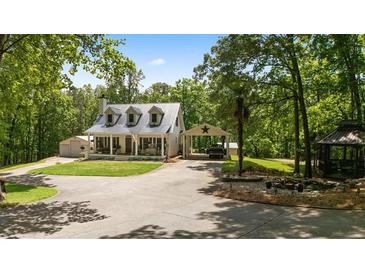 Charming home featuring a metal roof, covered porch, carport and a beautifully landscaped yard with mature trees at 291 Miquel Jorge Ln, Canton, GA 30115