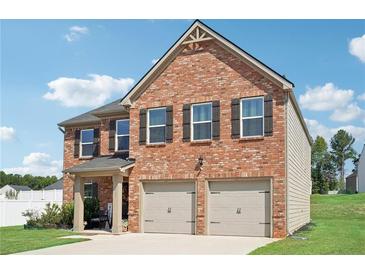 Charming two-story brick home with an attached two car garage and well-maintained lawn at 1363 Midnight Ride Ct, Hampton, GA 30228