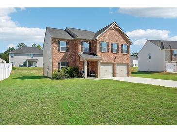 Two-story brick home with a two-car garage and landscaped lawn at 1363 Midnight Ride Ct, Hampton, GA 30228