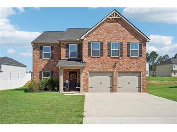 Brick two-story house with a two-car garage and a well-manicured lawn at 1363 Midnight Ride Ct, Hampton, GA 30228