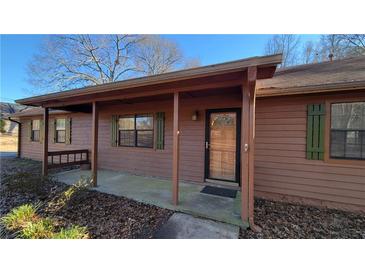 Ranch house with covered porch, brown siding, and green shutters at 557 Mccullough Rd, Stockbridge, GA 30281