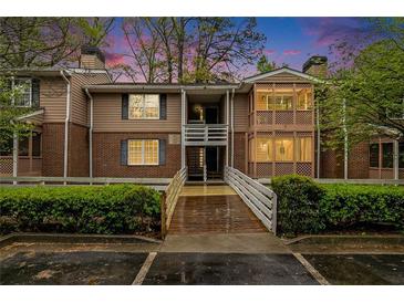 Brick condo building with a wooden walkway and lush landscaping at 261 Quail Run, Roswell, GA 30076