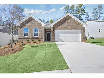 Charming brick home featuring a two-car garage, well-manicured lawn, and tasteful landscaping at 392 Village Ln, Fairburn, GA 30213