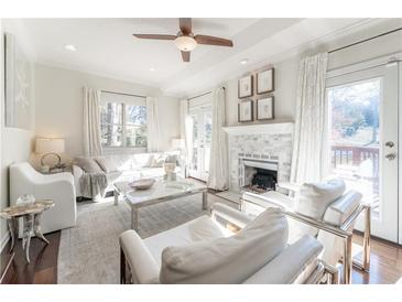 Bright living room featuring a fireplace, ceiling fan, and French doors leading to an outdoor space at 111 Swanton Hill Ct, Decatur, GA 30030