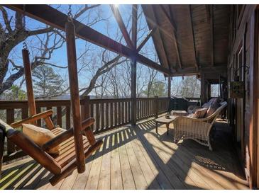 Inviting covered deck with swinging chairs, outdoor seating, and natural wood finishes for relaxing in the fresh air at 49 Holly Springs Ne Rd, White, GA 30184
