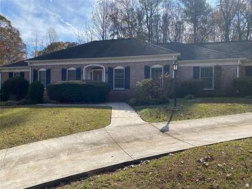 Charming brick home with a well-manicured lawn, mature trees, and a curved walkway leading to the front door at 229 Smithstone Path, Fayetteville, GA 30214