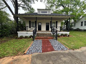 Charming home with inviting front porch, black railings, and a brick and gravel pathway to the front doors at 31 N Broad N St, Porterdale, GA 30014