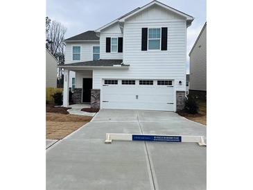 Two-story white house with a two-car garage and landscaped yard at 7520 Saffron Ave, Covington, GA 30014