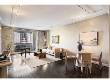 Bright living room features hardwood floors, modern furniture, neutral color scheme, and sliding glass doors to a balcony at 75 14Th St # 3640, Atlanta, GA 30309