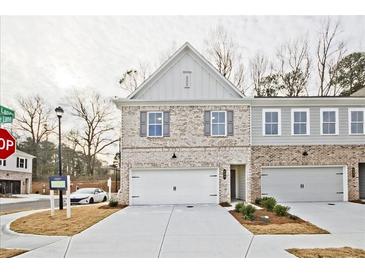 Charming townhouse with a white brick facade, two-car garage, and well-manicured lawn at 699 Sunstone Ln, Lawrenceville, GA 30043