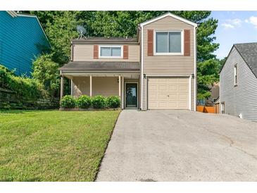 Charming two-story home featuring a well-manicured lawn, attached garage, and inviting front porch at 1184 Red Oak Cv, Tucker, GA 30084