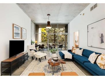 Bright living room featuring a blue sectional sofa and a large window with views to the outside balcony at 130 Arizona Ne Ave # 104, Atlanta, GA 30307