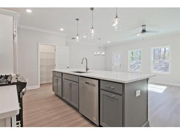 Open kitchen with gray cabinets, quartz countertops, stainless steel appliances, and pendant lighting at 689 Sunstone Ln, Lawrenceville, GA 30043