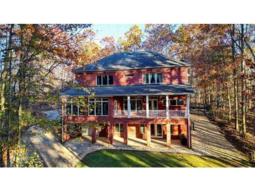 Stunning three-story red brick home with a balcony and a beautifully landscaped yard surrounded by autumn trees at 271 Brooks Rackley Rd, Dallas, GA 30157