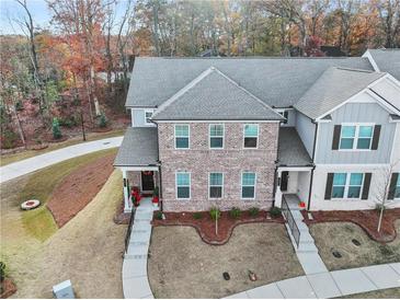 Beautiful brick townhome featuring a cozy porch, landscaped yard, and professional landscape in a well-maintained community at 691 Cordele Ln, Sugar Hill, GA 30518