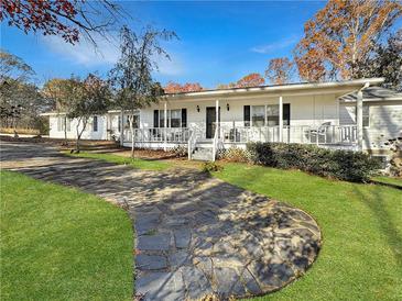 Charming home featuring a welcoming front porch and a beautifully landscaped yard with a stone walkway at 7440 Banks Mill Rd, Douglasville, GA 30135