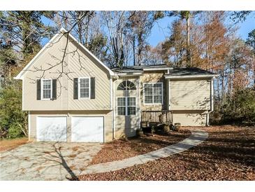 Tan two-story house with two-car garage and landscaped yard at 4760 Woodcrest Trl, Powder Springs, GA 30127