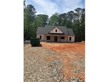 Exterior view of a new home under construction with a dark roof and light wood framing surrounded by trees at 542 Palm St, Holly Springs, GA 30115