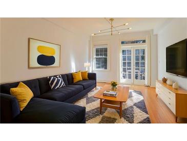 Comfortable living room with modern décor, a sectional sofa, artwork, and natural light from the French doors at 908 Juniper Ne St # 205, Atlanta, GA 30309