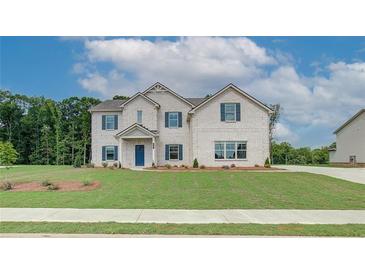 Charming two-story home with a brick facade, blue shutters, well-manicured lawn and professional landscaping at 173 Haverling Pass, Hampton, GA 30228