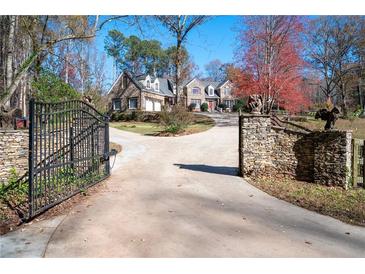 Gated driveway leading to a charming stone home with well-manicured landscaping and mature trees at 355 Clark Creek Pass, Acworth, GA 30102