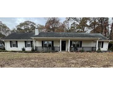 Ranch style home with white exterior, covered porch, and mature trees at 1678 Se Christian Cir, Conyers, GA 30013