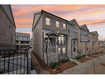 Charming brick townhome showcasing a lovely front porch and professional landscaping at 4145 Essex Pond Way, Cumming, GA 30040