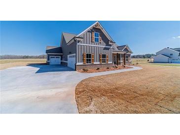 Beautiful modern farmhouse with gray siding, wood accents, and a large driveway on a sunny day at 1422 Alcovy Station Rd, Covington, GA 30014
