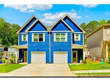 Charming, bright blue, two-story townhome featuring white trim, individual garages, and manicured lawn at 3108-A Brownstone Se Ln, Atlanta, GA 30354