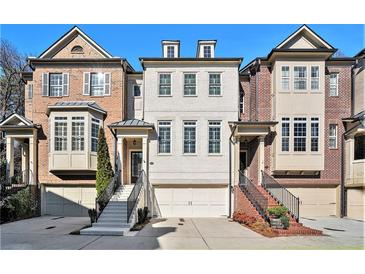 Three story townhome featuring attached garages, front staircases, and a mixture of brick and painted exteriors at 3693 Broughton Se Cir, Atlanta, GA 30339