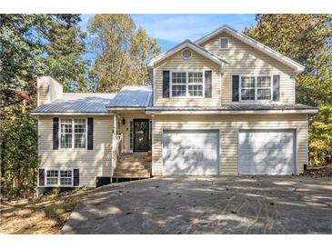 Charming two-story home with a metal roof, a two-car garage and nicely landscaped front yard at 34 Clay Ct, Villa Rica, GA 30180