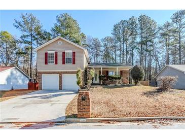 Beige house with red shutters, two-car garage, and a landscaped yard at 3100 Aberdeen Way, Lithonia, GA 30038