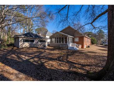 A backyard with a home, an enclosed porch, an outbuilding, and a ground covered with fallen leaves at 341 Little John Nw Dr, Lilburn, GA 30047