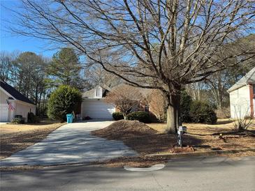 Ranch home with attached garage and driveway, nestled amongst mature trees at 341 Little John Nw Dr, Lilburn, GA 30047