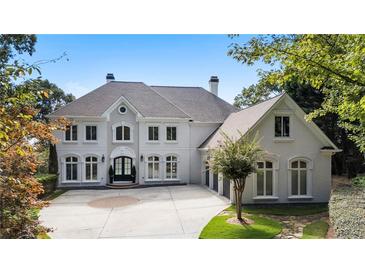Stunning two-story home with a grand entrance, a circular driveway, and manicured landscaping at 8380 Sentinae Chase Dr, Roswell, GA 30076