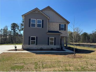 Two-story home featuring gray siding, brick accents, and black shutters set against a clear blue sky at 1641 Fuma Leaf Way, Mcdonough, GA 30253