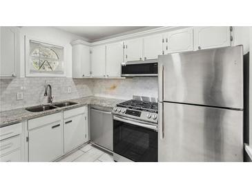 This kitchen features stainless steel appliances, white cabinets, granite countertops, and a double sink at 5400 Roswell Rd # C3, Atlanta, GA 30342