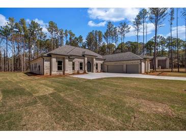 Stunning single-story home featuring a symmetrical facade, manicured lawn and a three car garage at 125 Drummond Pl, Covington, GA 30014