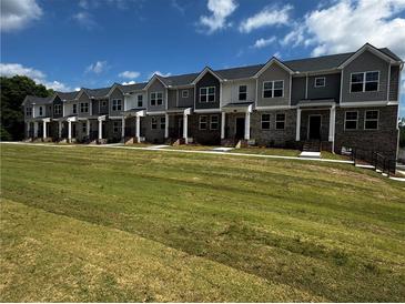 New two-story townhomes featuring brick accents, gray siding, multiple windows and a well-manicured lawn at 989 Cades Walk, Lawrenceville, GA 30045