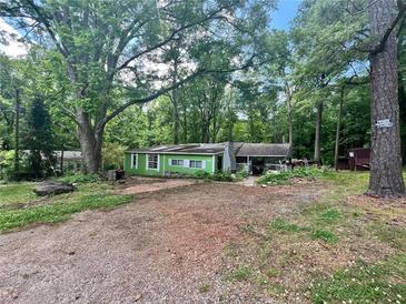 Quaint single-story home with a covered porch nestled among mature trees in a private, wooded lot at 202 Hayes St, Villa Rica, GA 30180