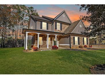 Charming two-story home with a landscaped yard, covered porch, and stone and siding accents at 324 Mary Dr, Mcdonough, GA 30252