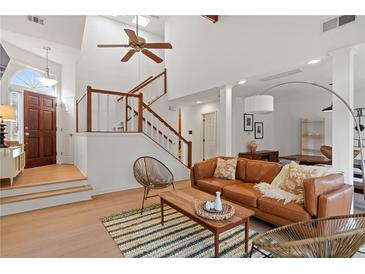 Inviting living room with vaulted ceiling, hardwood floors, modern furniture, and a staircase with white and wood railing at 1827 Rockridge Pl, Atlanta, GA 30324