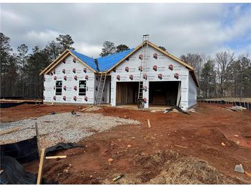 Exterior view of new construction showcasing the home's framing, wrapped with protective material and a blue-covered roof at 1586 Sungrown Way, Mcdonough, GA 30253