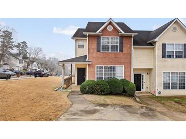 Two-story townhouse with brick and vinyl siding, a covered front porch, and mature landscaping at 1450 Riverrock Trl, Riverdale, GA 30296
